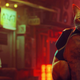 The cat protagonist of Stray sits with a backpack device.